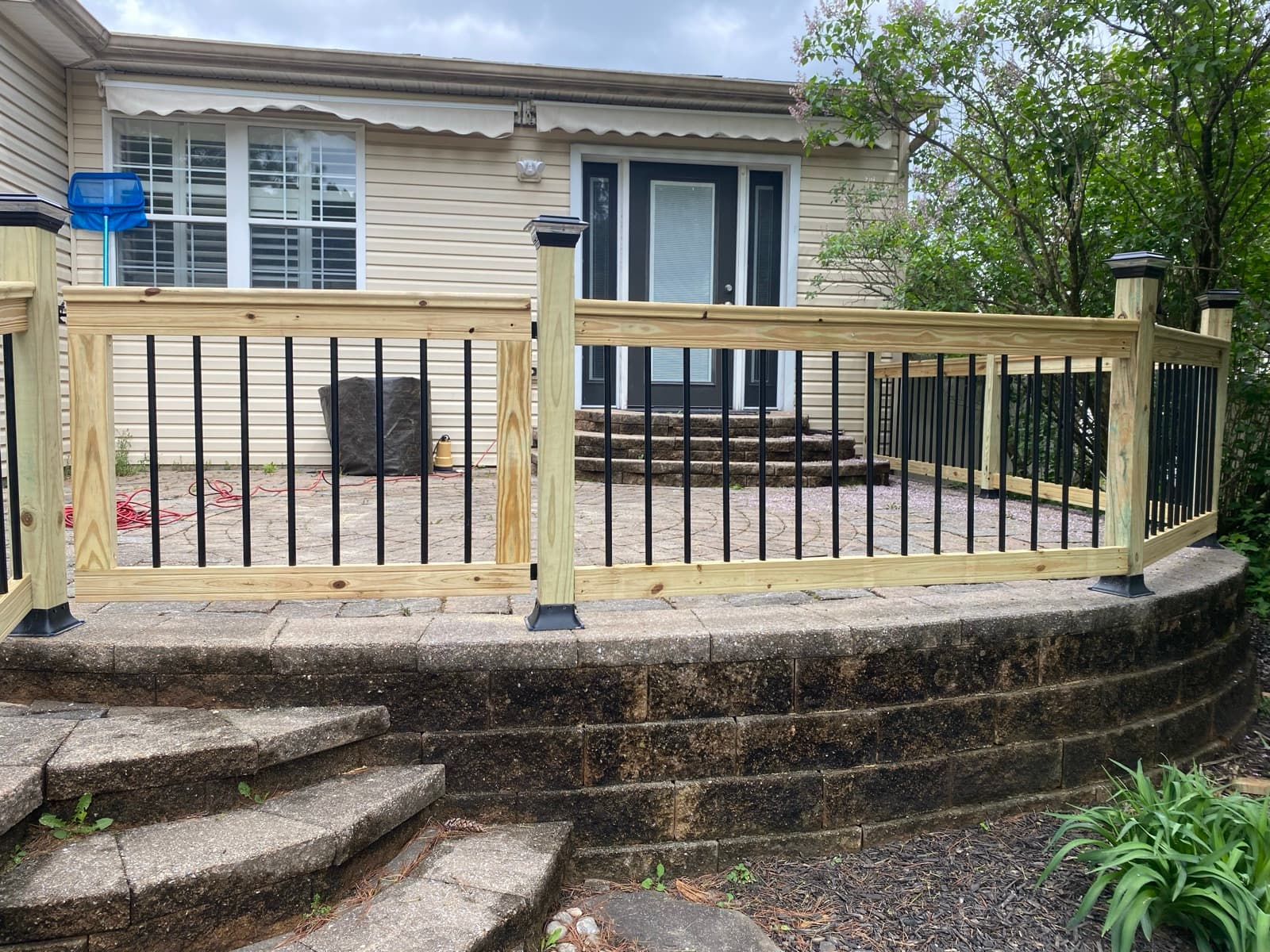 Custom cedar and black metal railing around a paver patio in Northampton, PA