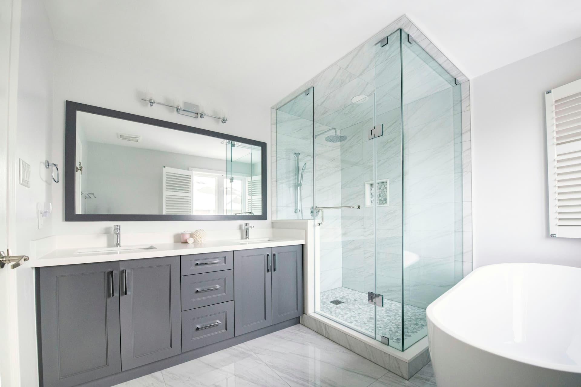 Bright remodeled bathroom with a glass shower, double vanity, and freestanding tub