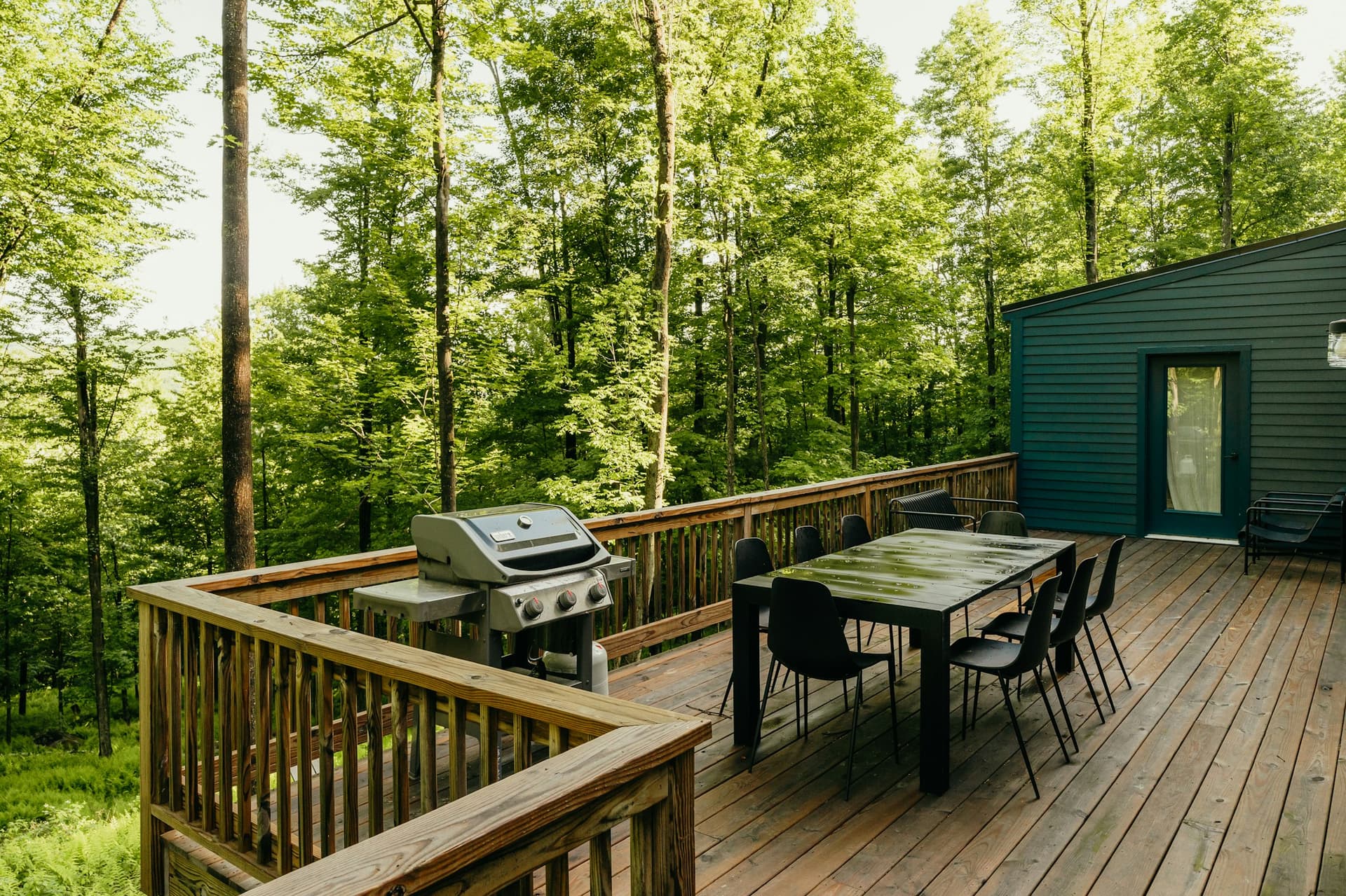 Wooden backyard deck with outdoor dining and a wooded view